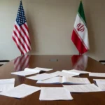 Mesa de negociações com bandeiras dos EUA e Irã sobre acordo diplomático
